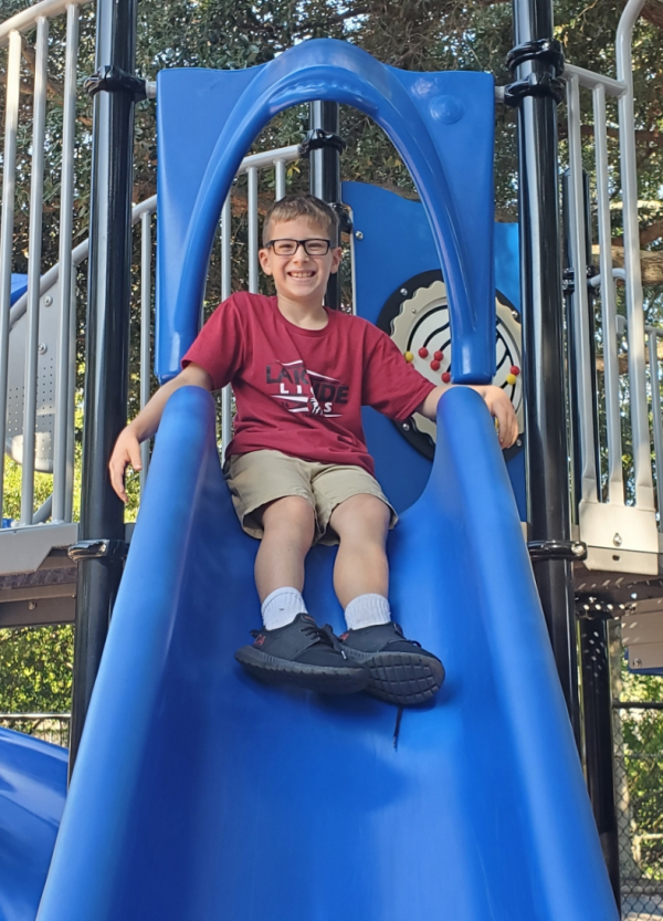a smiling private school student at Lakeside Christian School in CLearwater, Fl goes down the slide on the playground