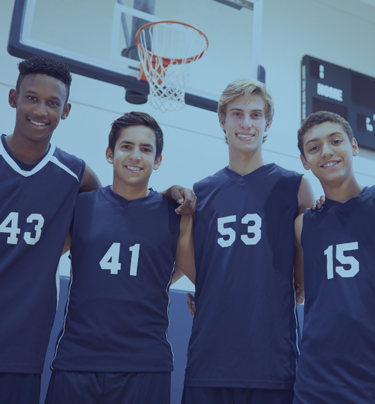 a group of male high school basketball players at a private Chrsitian school in Clearwater, Fl called Lakeside Christian School, are wearing blue and white jerseys and smiling into the camera with their arms around each other.