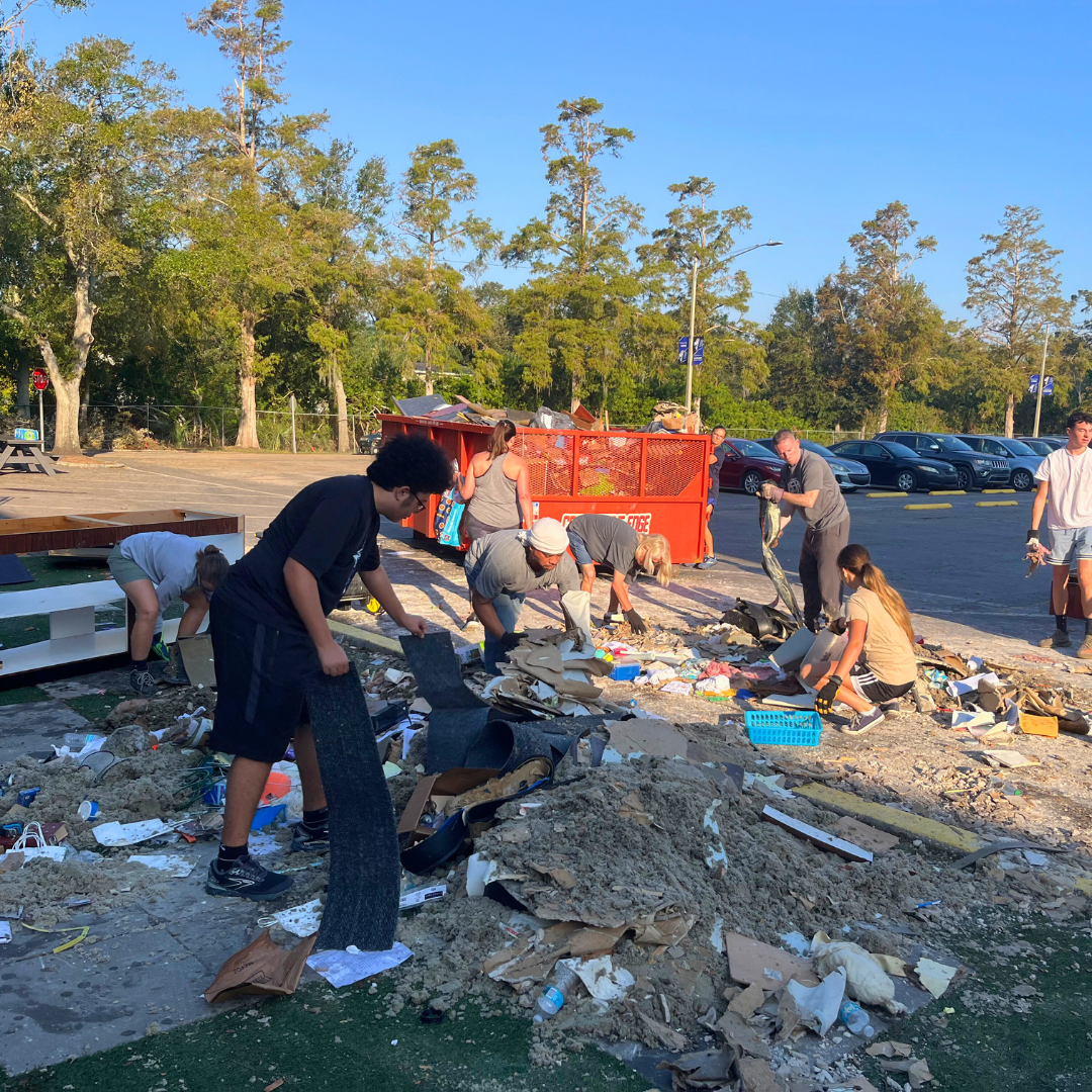 a group of students, staff, and parents at Lakeside Christian School in CLearwater, Fl, work together in teh school parking lot to clear water damaged debris due to Hurricane Milton.