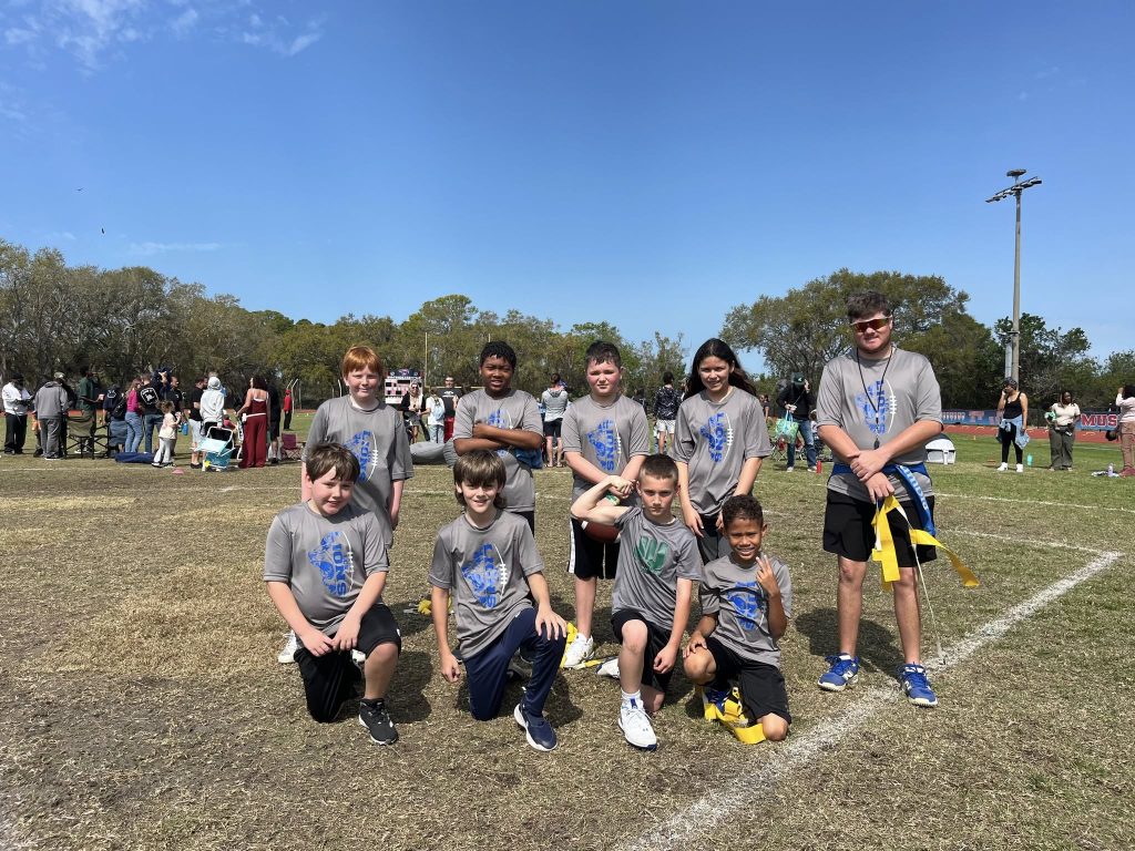 Lakeside Christian School’s 3rd-5th grade flag football team poses with their coaches on the field after a successful season, showcasing teamwork, sportsmanship, and school spirit.